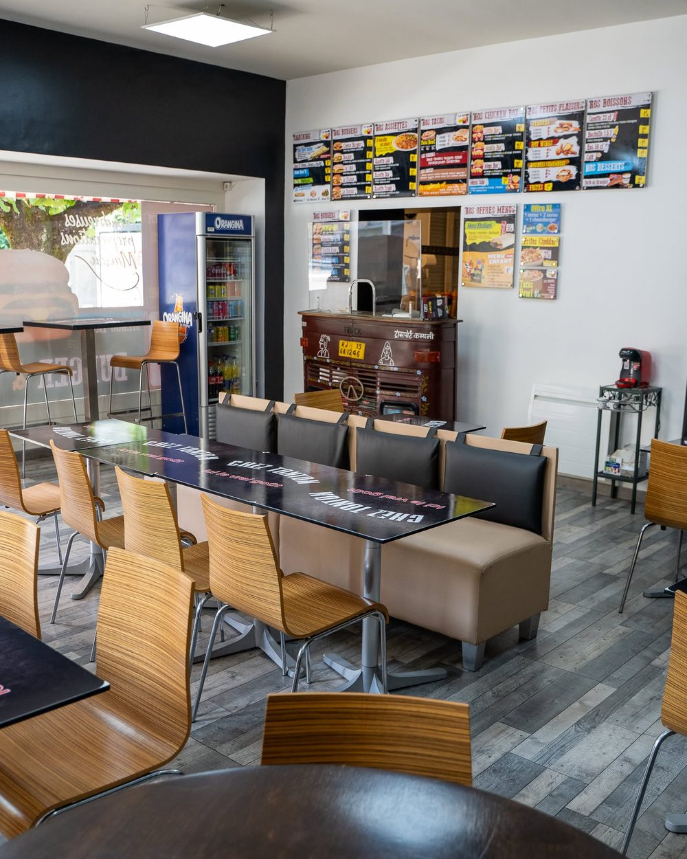 Salle de Chez Tonton : tables, banquette et menus affichés au mur